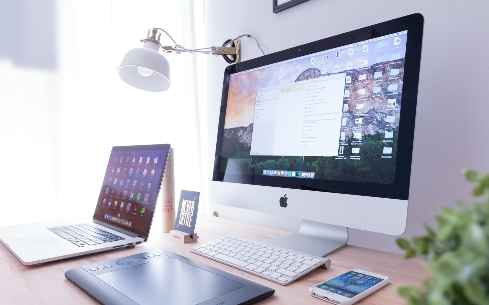 A desktop computer, laptop and phone set up together on a desk