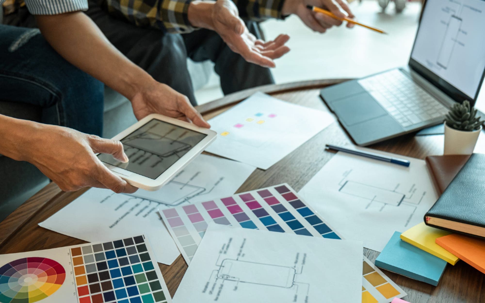Colleagues comparing printed plans and a tablet across a desk